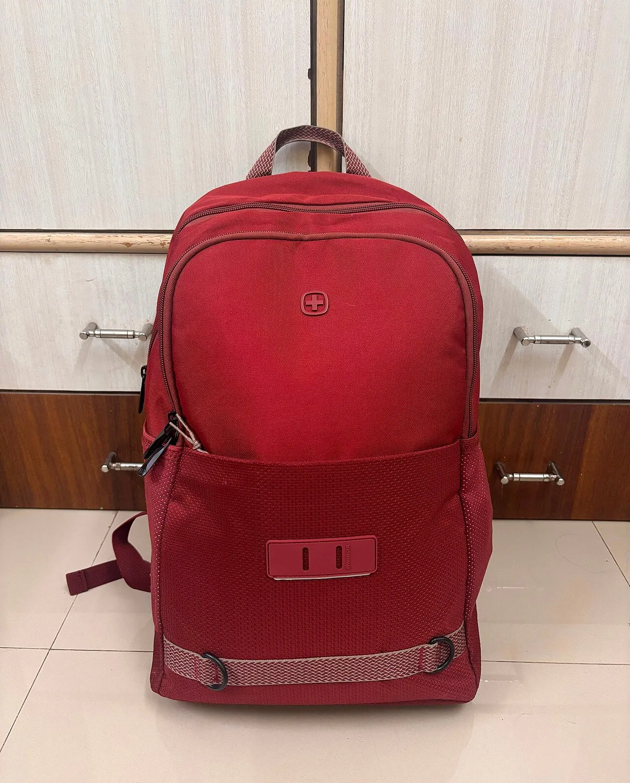 Red backpack standing against a light-colored wall