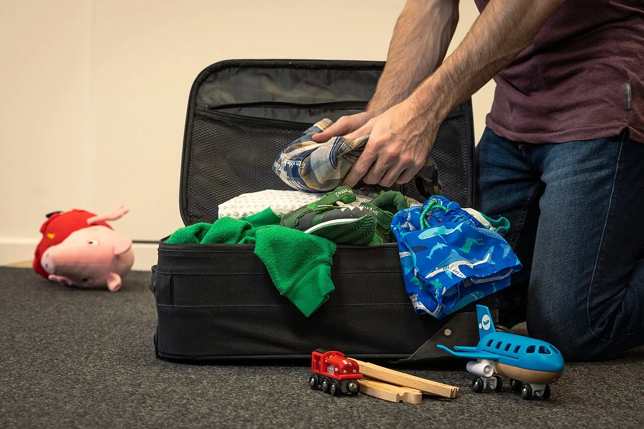 An open suitcase with clothes and small travel items laid out for packing
